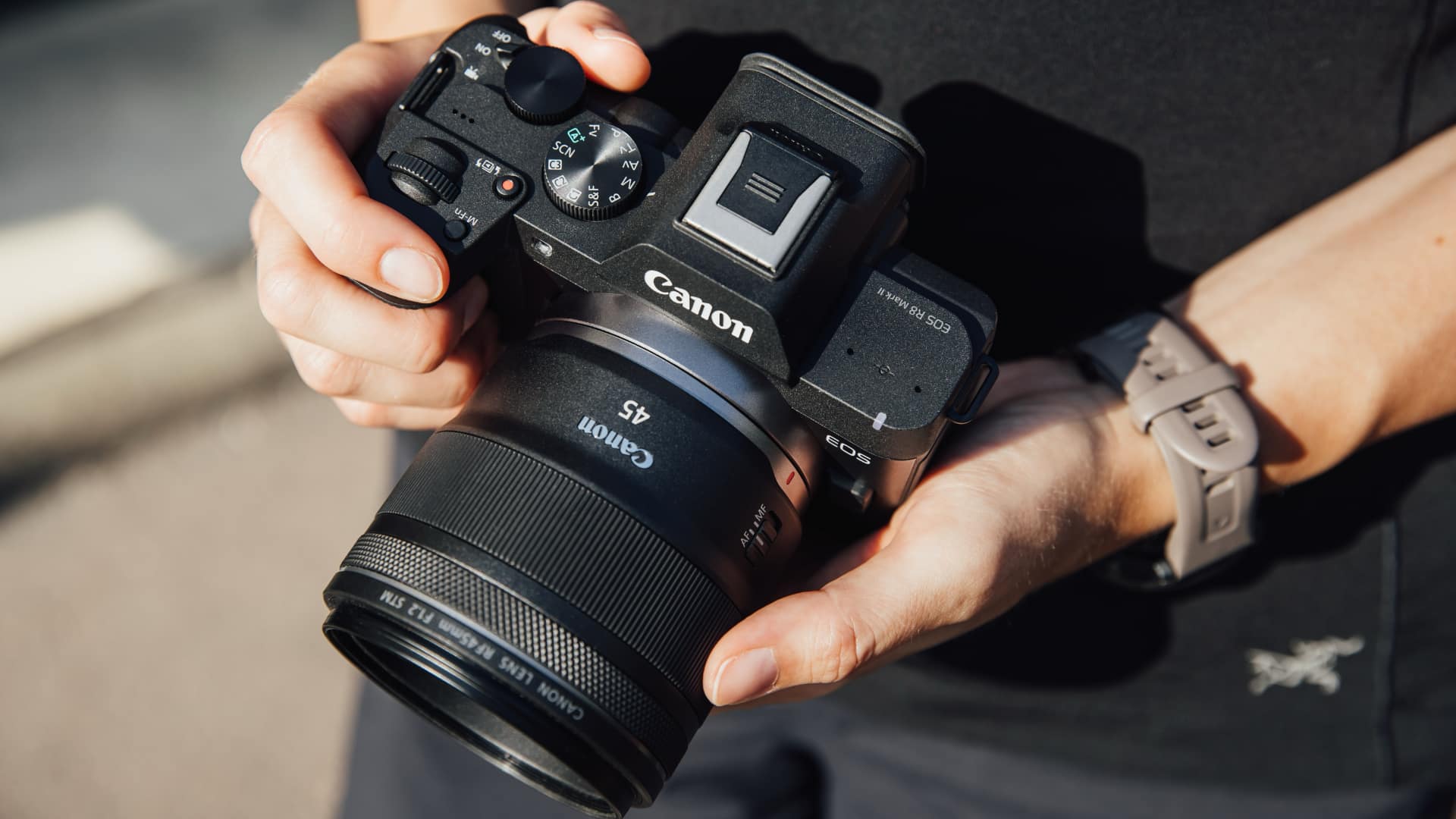 Hands holding the Canon EOS R8 Mark II fitted with the RF 45mm F1.2 STM lens outdoors