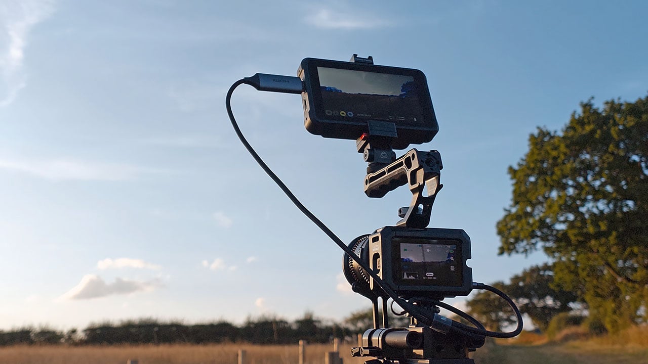 GoPro Mission 1 Pro ILS rigged with an external monitor on an articulating arm, shot outdoors on a tripod