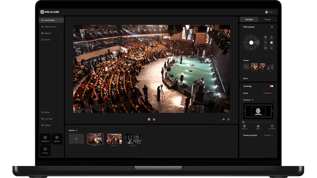 Hollyland Astra P1 browser-based control interface on laptop showing live preview of auditorium, PTZ controls, preset scenes, and AI tracking settings