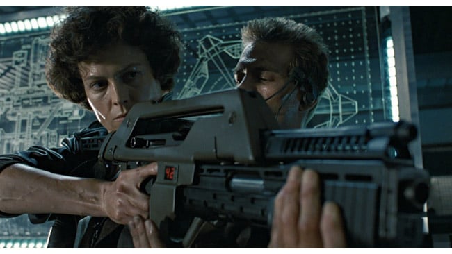 If it's OK to use a famous example, consider this. The weapon looms; the background is the display board. These are not chance happenings (from Aliens).jpg