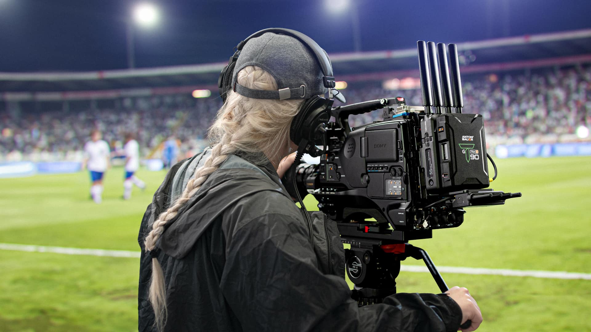 Camera operator filming a night football match with a Sony camera rig fitted with a Teradek transmitter.