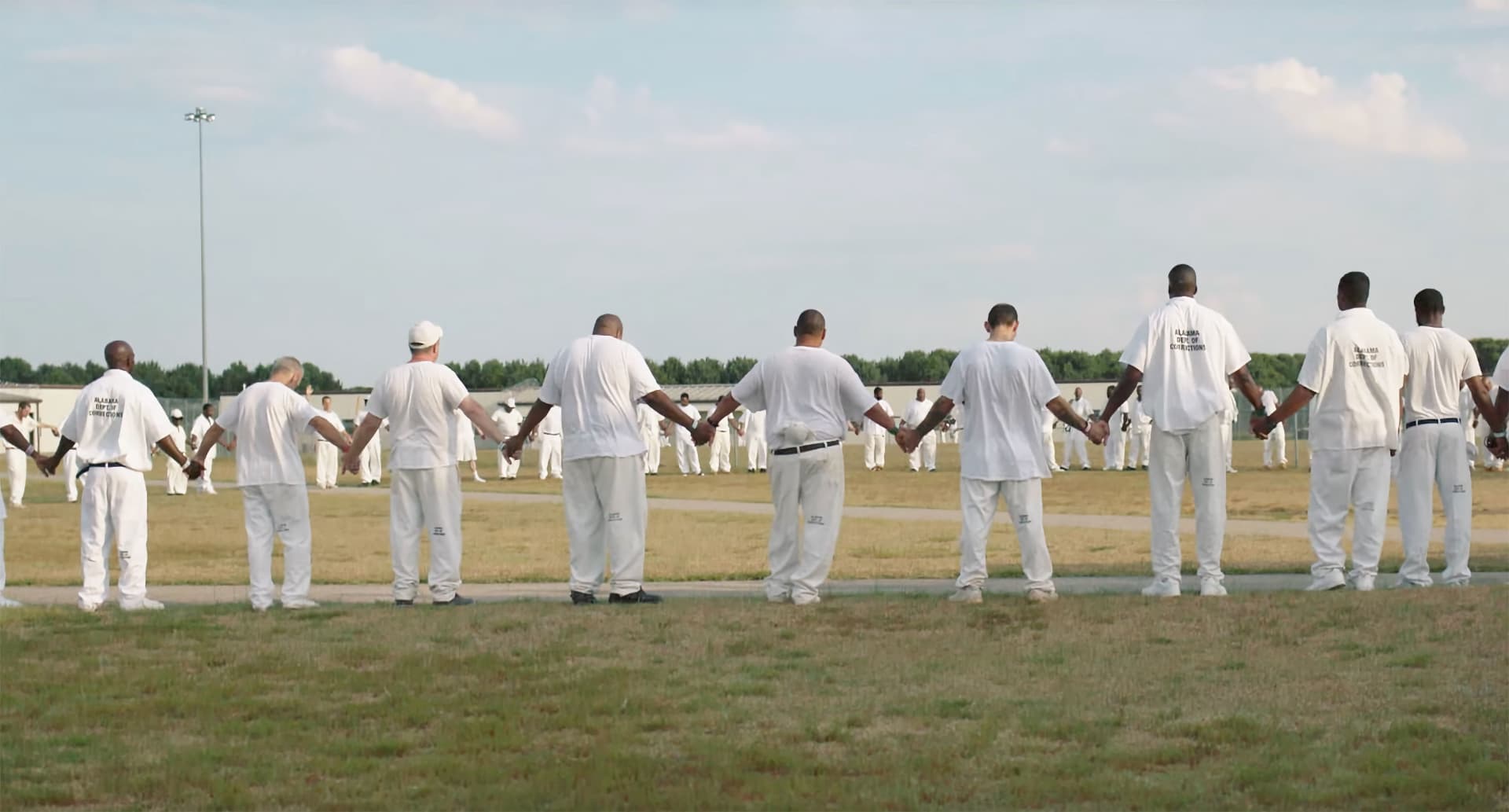 Inmates stand in a large circle in The Alabama Solution