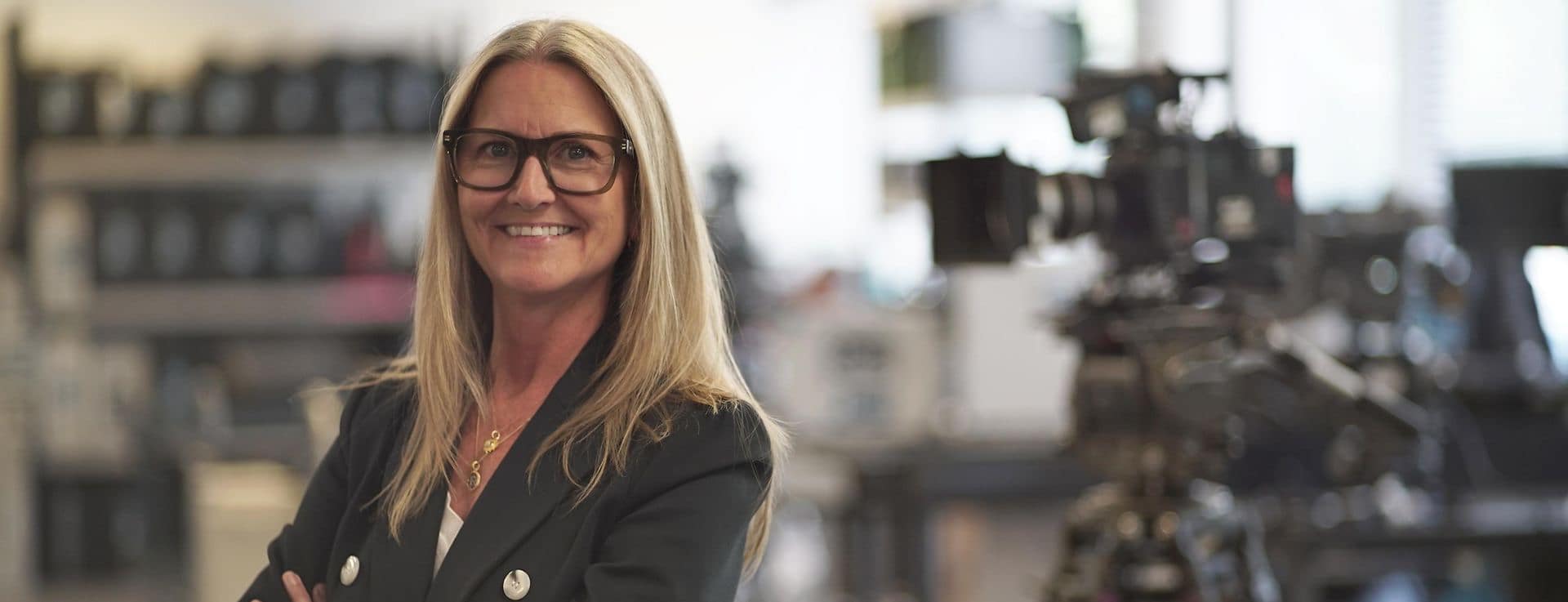 ARRI Rental CEO, Dana Harrison, looing directly at camera with out of cosue camera equipment in the background behind