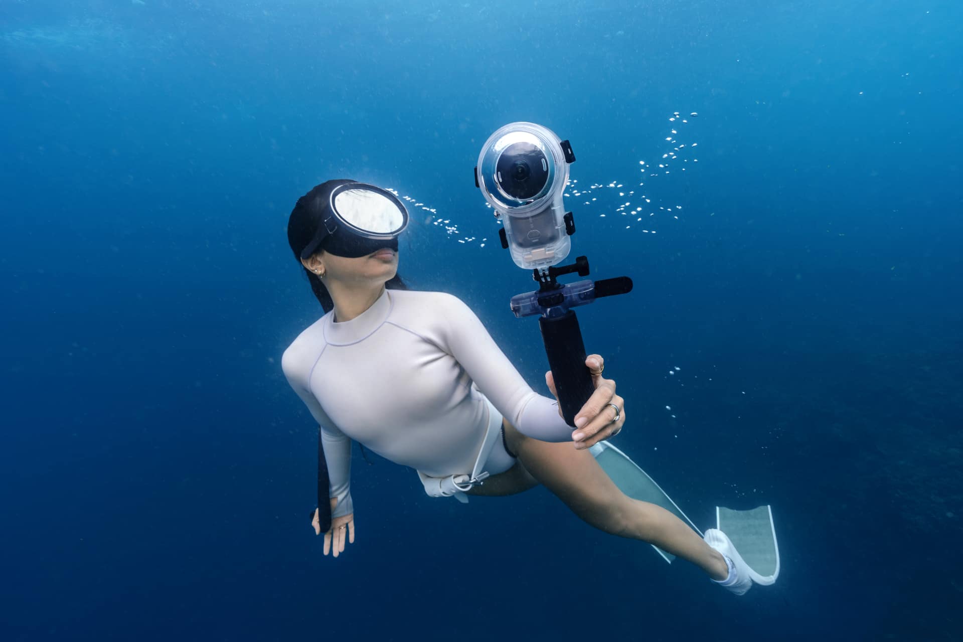 Freediver holding Insta360 X6 in the Invisible Dive Case Pro underwater on a selfie stick