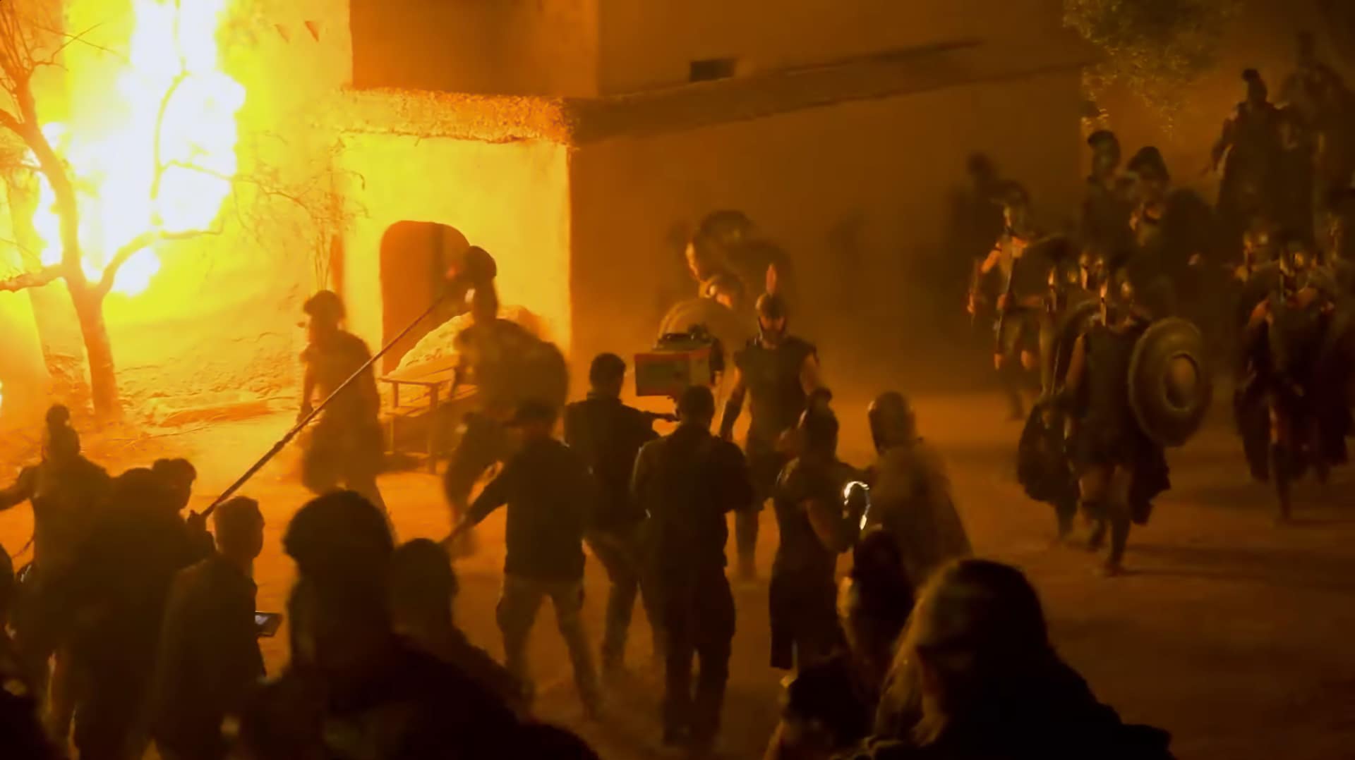 Camera operator running with a harnessed IMAX camera rig during a nighttime battle scene on The Odyssey