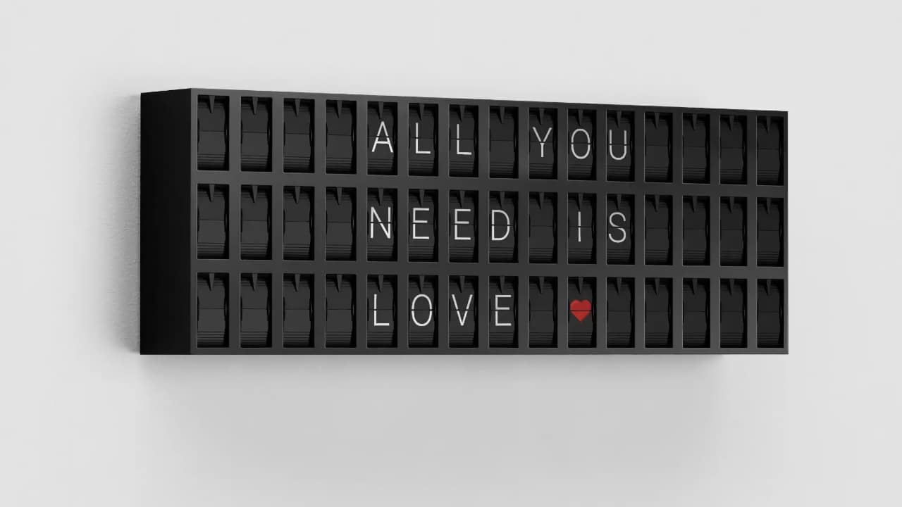 Vestaboard Note split-flap message board on a gray background displaying ALL YOU NEED IS LOVE with a red heart